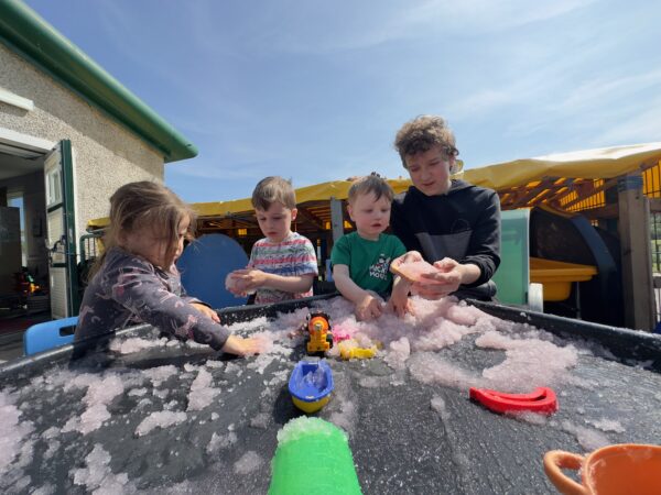 Teenager mentoring young children in a nursery